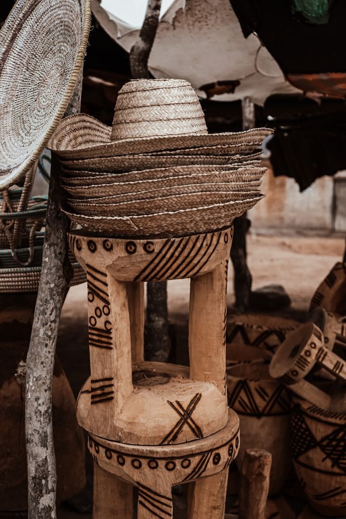 gallery-6 Explore a traditional Angolan market displaying rustic woven hats and decorative wooden carvings.