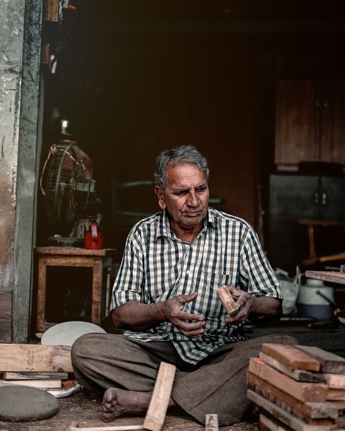 our-services-1 South Asian craftsman working with wood in a rustic workshop in Kalol, India.