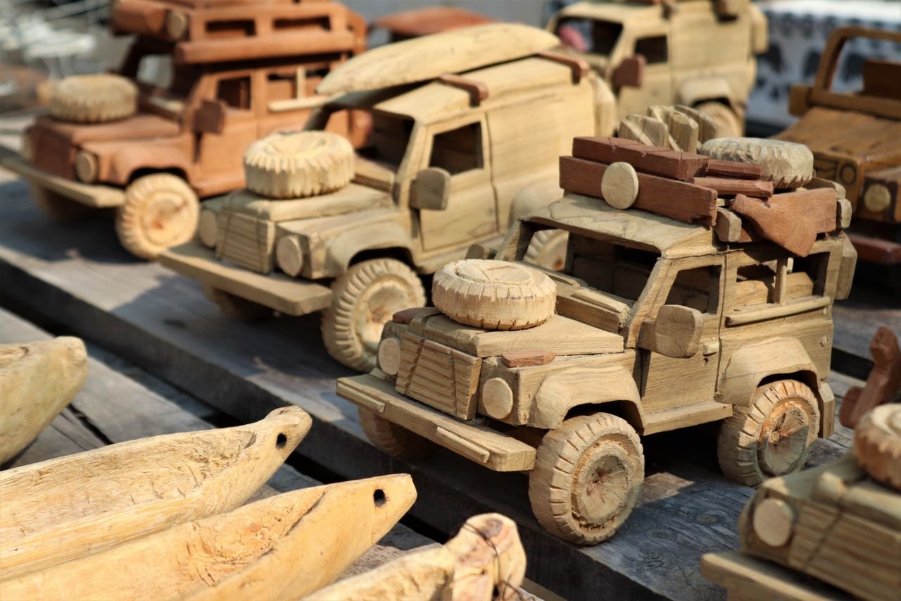 hero-img-02 A selection of intricately carved wooden toy trucks displayed at a market. Perfect for souvenirs.