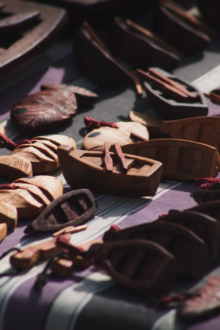 Intricately carved wooden boats and figures showcased outdoors in Alger, Algeria.