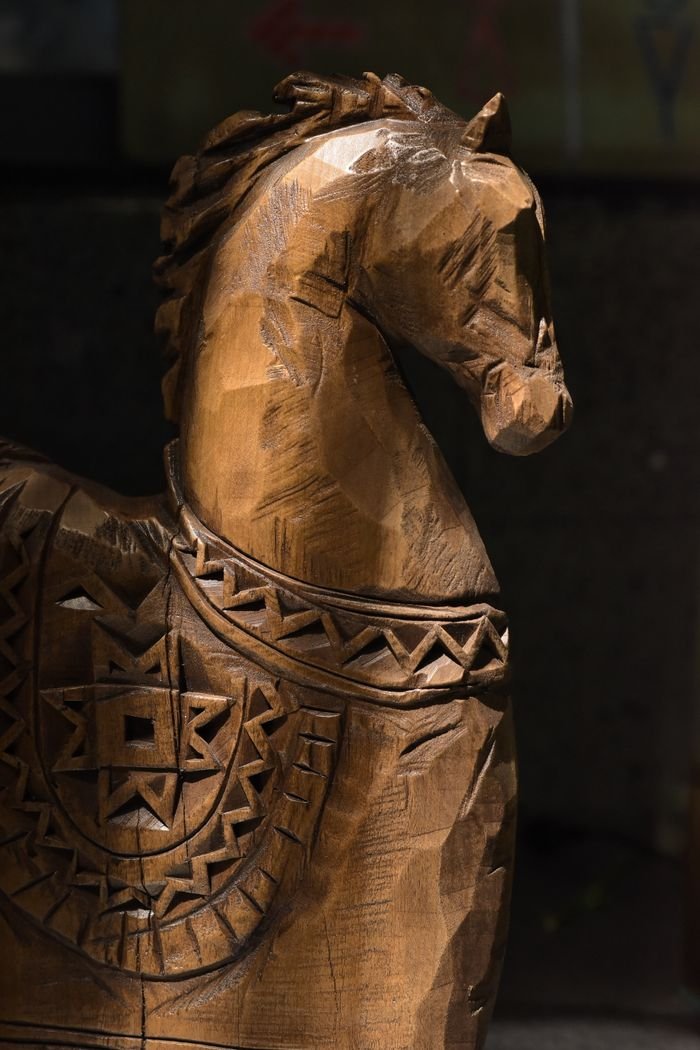 Close-up of a carved wooden horse showcasing detailed geometric patterns and warm lighting.