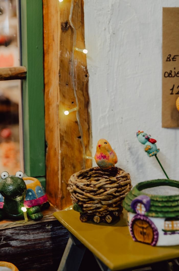 A variety of colorful handcrafted decorations including birds and nests on a shelf.
